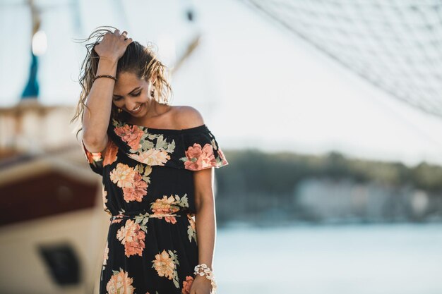 An attractive young woman in flower dress spending summer vacation at the seashore.