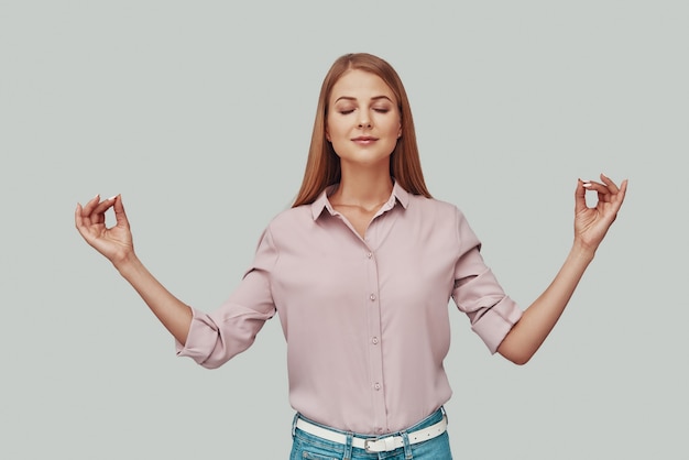 Photo attractive young woman gesturing and smiling while standing against grey background