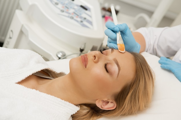 Attractive young woman getting facial mask at the spa