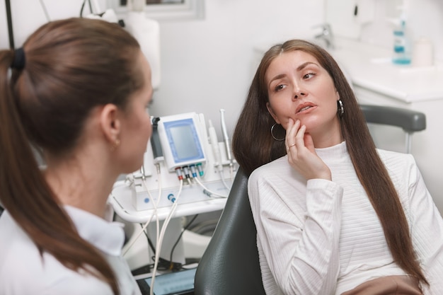 Attraente giovane donna con mal di denti, visitando il dentista