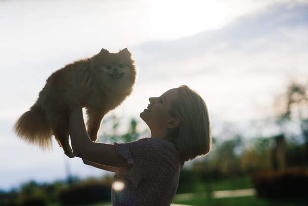 Attractive young woman holding dog spitz  in the park.