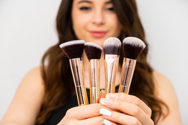 Attractive young woman holding golden makeup brushes Professional makeup artist concept