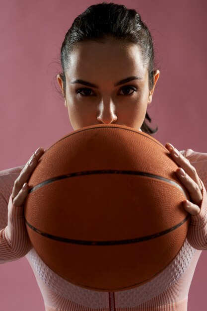 Attractive young woman holding orange basketball ball