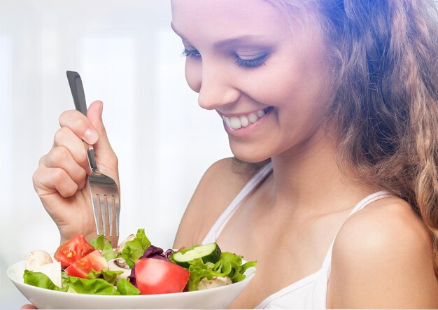Attractive young woman holding salad and smiling at camera