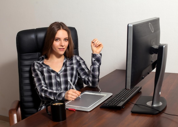 Attractive young woman is sitting in front of computer and going to do her retouching work