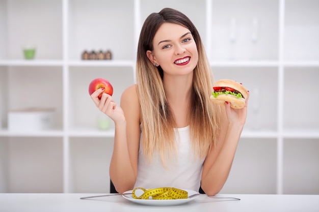 La giovane donna attraente fa una scelta tra sano e non sano