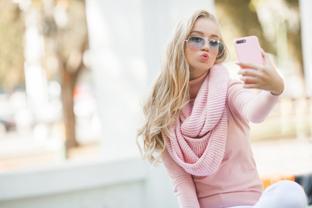 Giovane donna attraente che rende selfie all'aperto