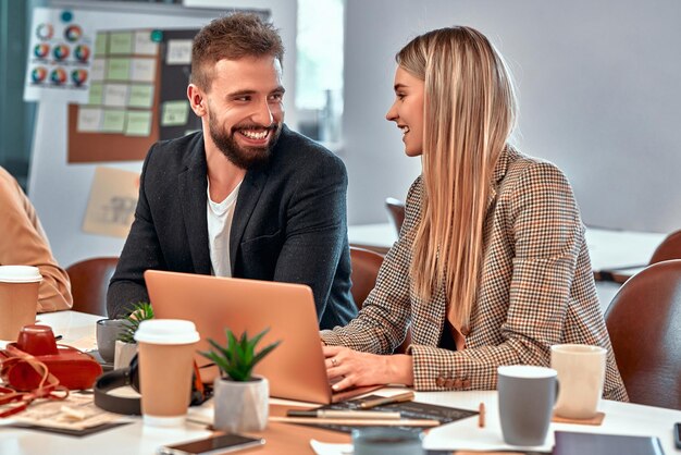 Photo an attractive young woman and man sitting reading a laptop screen together as collaborate as a team