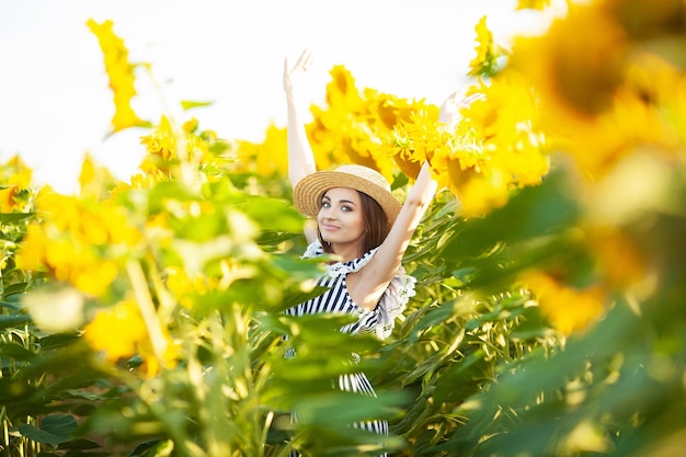 Модель привлекательной молодой женщины позирует в поле подсолнухов