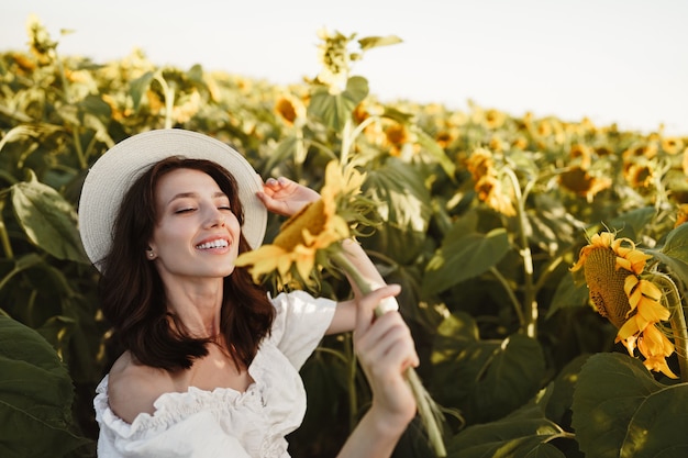 Attractive young woman model posing in field of sunflowers