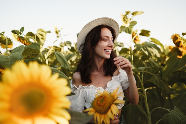 Attractive young woman model posing in field of sunflowers