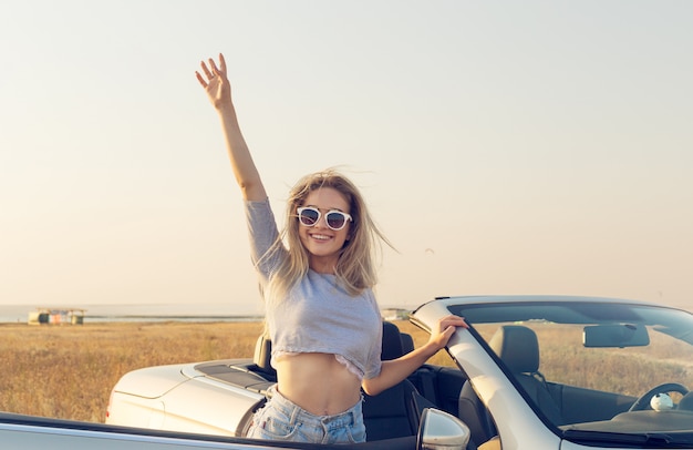  attractive young woman near a convertible car