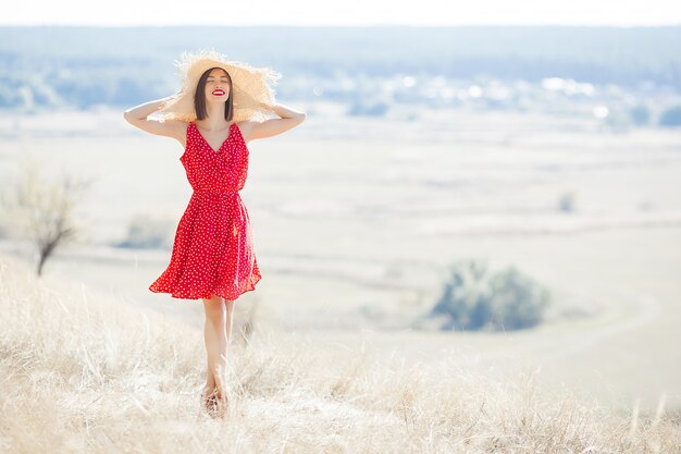 매력적인 젊은 여자를 야외에서. 빨간 드레스와 빨간 립스틱을 입고 레이디입니다. 아름 다운 여성 모델의 초상화를 닫습니다.