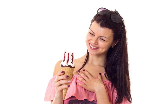 Attractive young woman in pink dress with palm trees and black sunglasses eating icecream