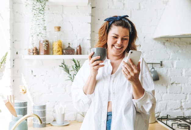 Attractive young woman plus size body positive in blue jeans\
and white shirt using cellphone