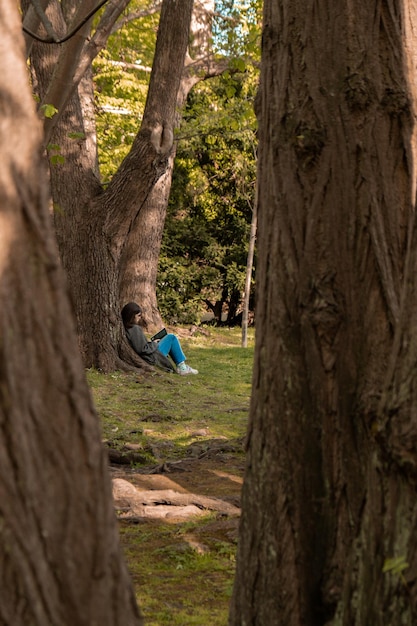 Привлекательная молодая женщина читает книгу, сидя на траве в зеленом общественном парке Весна на открытом воздухе Зелень в единстве с природой Проводит свободное время на открытом воздухе