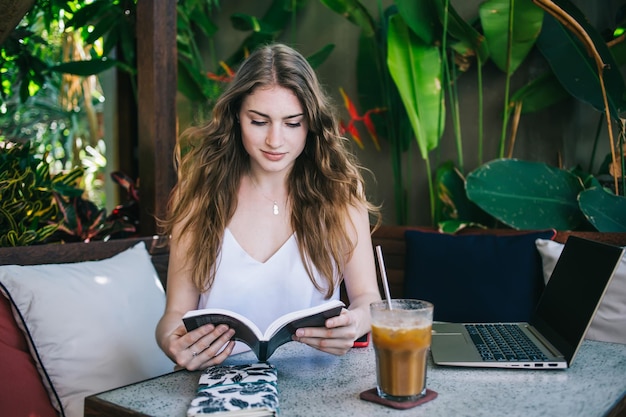 Attractive young woman reading in summer cafe