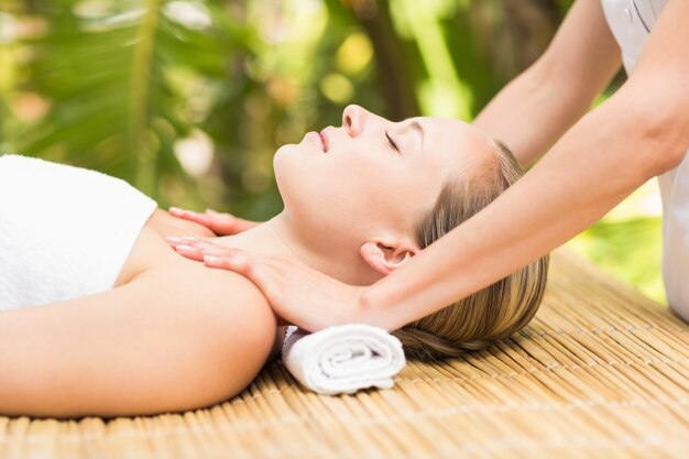 Attractive young woman receiving facial massage at spa center