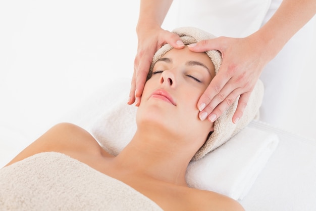 Attractive young woman receiving facial massage at spa center