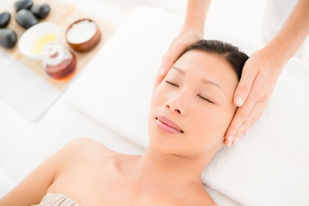 Attractive young woman receiving head massage at spa center