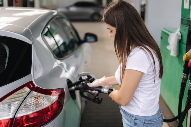 ガソリンスタンドで車に給油する魅力的な若い女性車のガソリン燃料でディーゼルを充填する女性