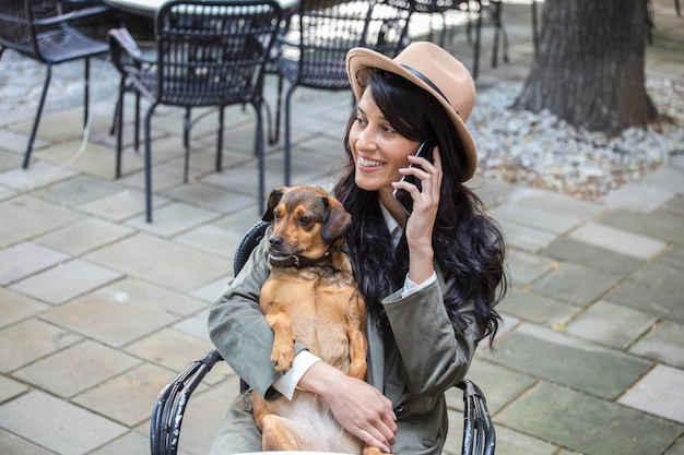 Attractive young woman sitting in coffee shop relaxing and
holding her dog pet friendly cafeteria beautiful girl with her dog
siting at a coffee shop and drink coffee