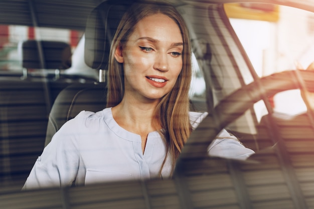 Attractive young woman sitting in new car in showroom close up