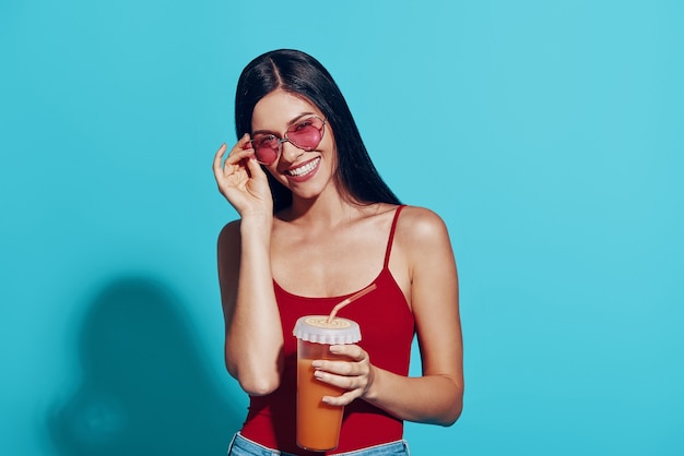 Attractive young woman  and smiling while standing against blue wall