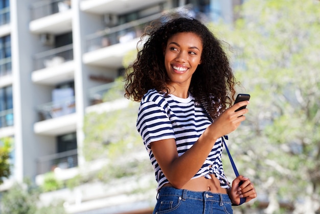 Attractive young woman smiling with cell phone outdoors