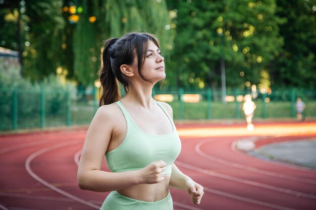 スタジアムでジョギングをしているスポーツウェアの魅力的な若い女性