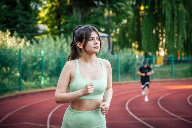 スタジアムでジョギングをしているスポーツウェアの魅力的な若い女性