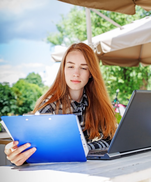 밖에 서 노트북을 사용 하여 매력적인 젊은 여자 학생