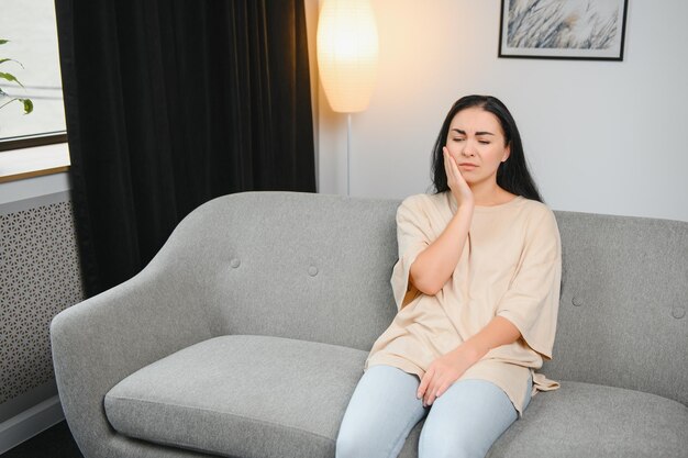 Attractive young woman suffering from toothache Woman holding her cheek in pain