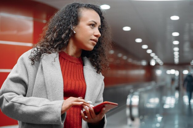 Attractive young woman taking a video call while standing in a subway tunnel