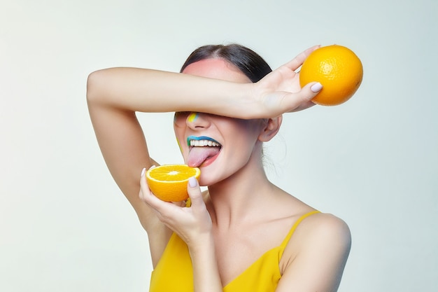 Attractive young woman touched her tongue to a slice of orange