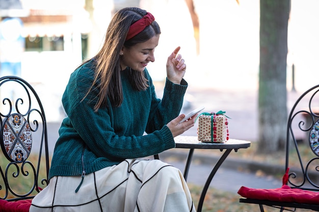 La giovane donna attraente utilizza lo shopping online di natale dello smartphone