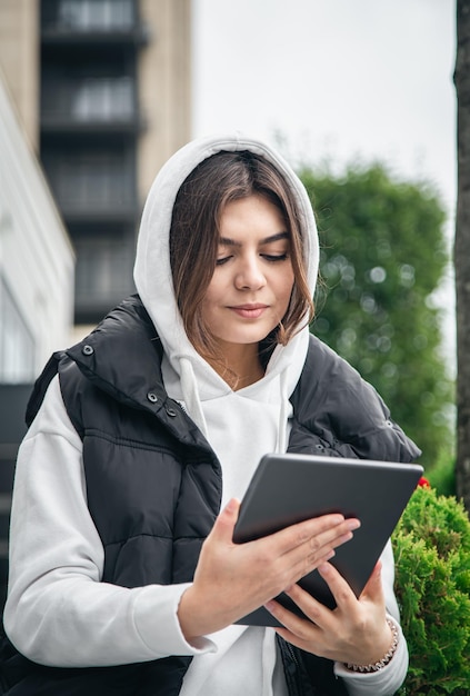 Attractive young woman uses a tablet communicates by video call outside