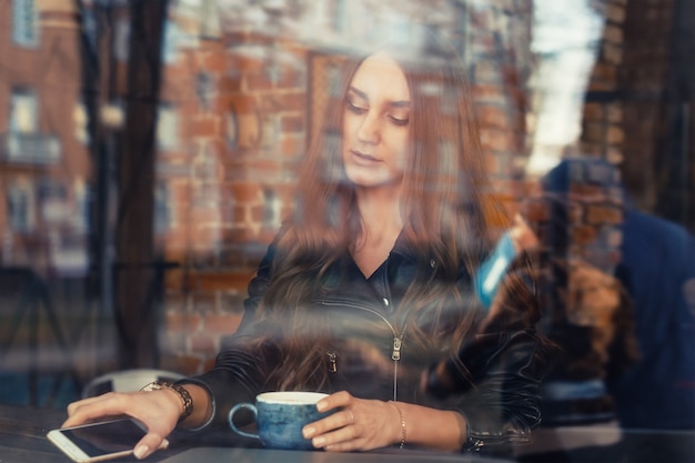 Привлекательная молодая женщина, с помощью мобильного телефона в кафе