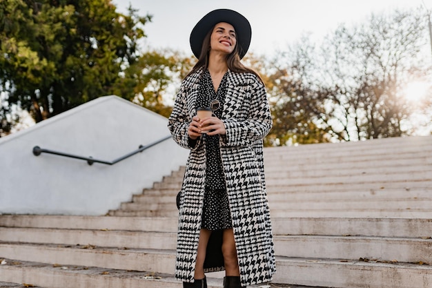 Foto giovane donna attraente che cammina in cappotto d'uso di autunno