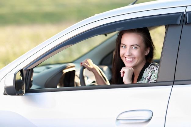 Attractive young woman at the wheel in her new car