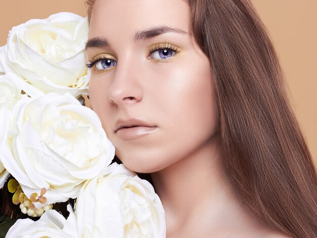 Attractive, young woman on a white background. Portrait of a beautiful girl with a bouquet of white flowers.