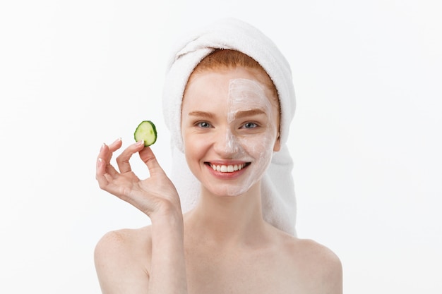 Attractive Young Woman with beautiful clean skin. White mask and cucumbers. Beauty treatments and cosmetology spa therapy. 