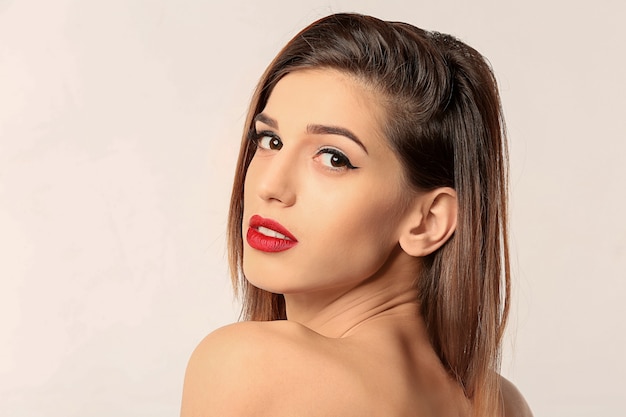 Attractive young woman with elegant makeup and long eyelashes on white.