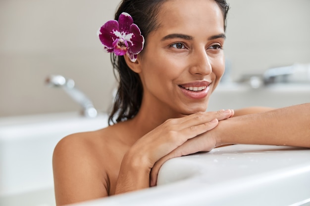 Attractive young woman with flower in her hair taking bath