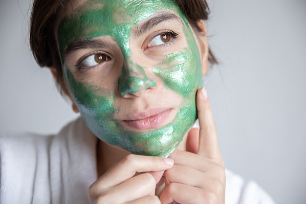 그녀의 얼굴에 녹색 화장품 마스크와 매력적인 젊은 여자