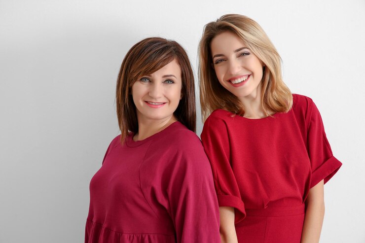 Photo attractive young woman with her mother in matching dresses on white background