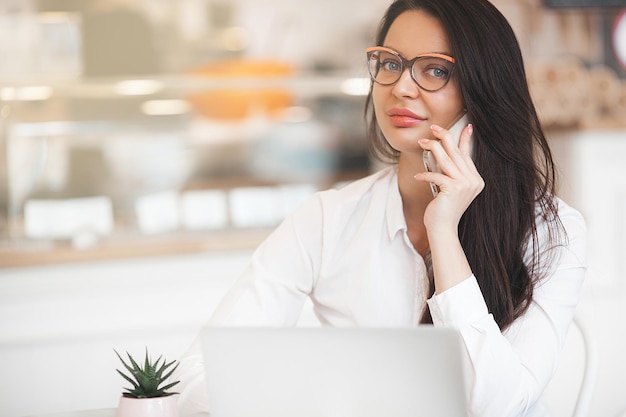 Attractive young woman with laptop Female in cafeteria with gadgets Busuness woman indoors