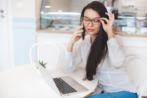 Attractive young woman with laptop Female in cafeteria with gadgets Busuness woman indoors