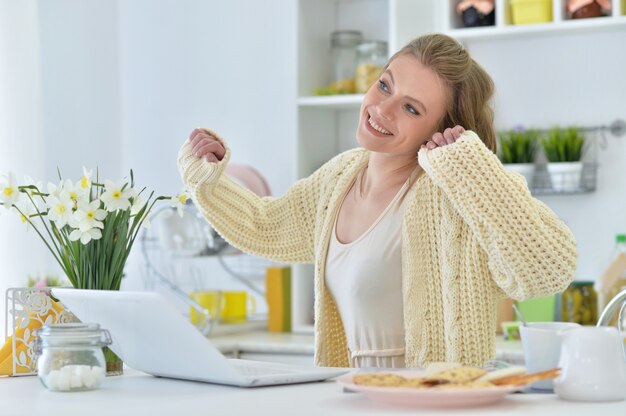 Photo attractive young woman with laptop at kitchen