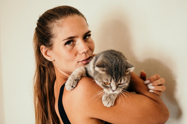 Attractive young woman with long hair embracing her pet with smile indoor portrait of cute woman